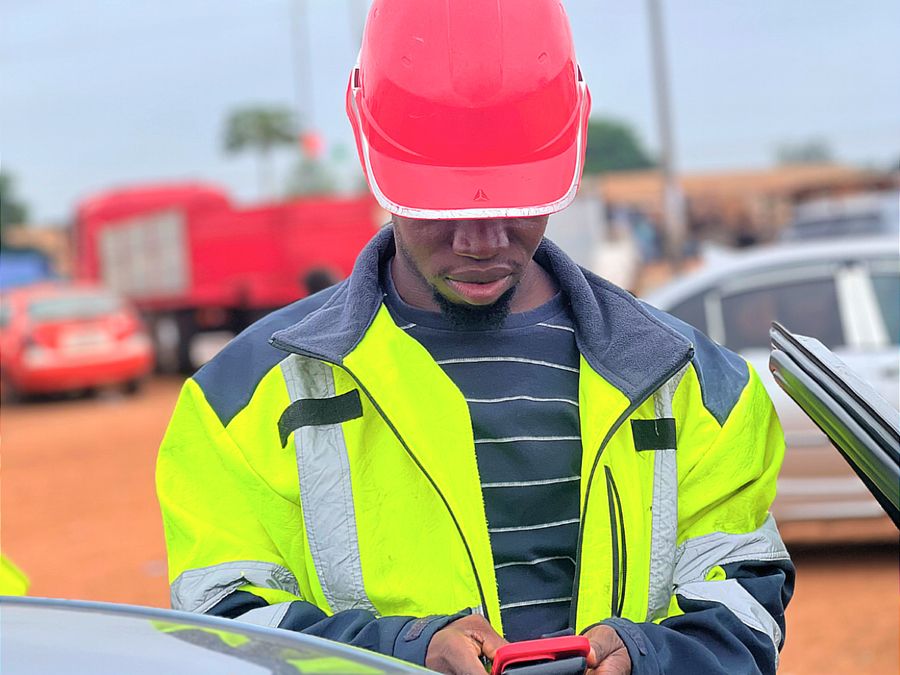 Technicien MBS en gilet et casque consultant son téléphone sur le terrain